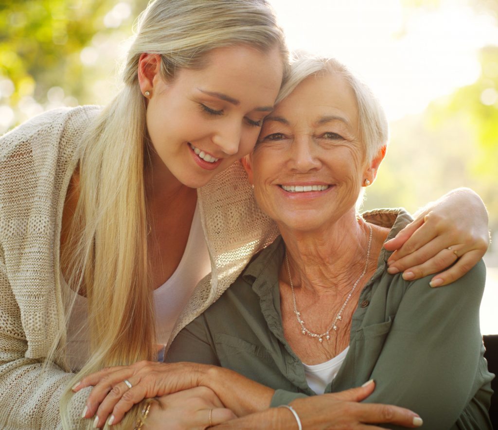 woman hugging her mother sitting in a wheelchair